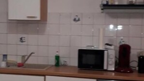 Uma cozinha com armários brancos, micro-ondas, máquina de café e lava-louças.