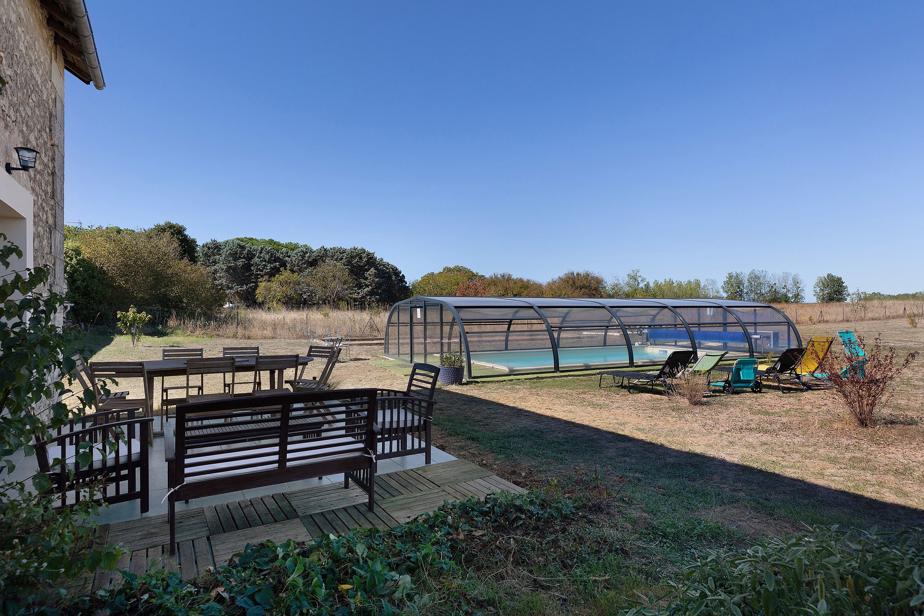 Un espace extérieur abrité comprenant une piscine, des sièges et une pergola.