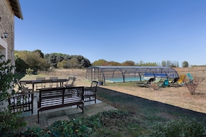 Ein überdachter Außenbereich mit Pool, Sitzgelegenheiten und einer Pergola.