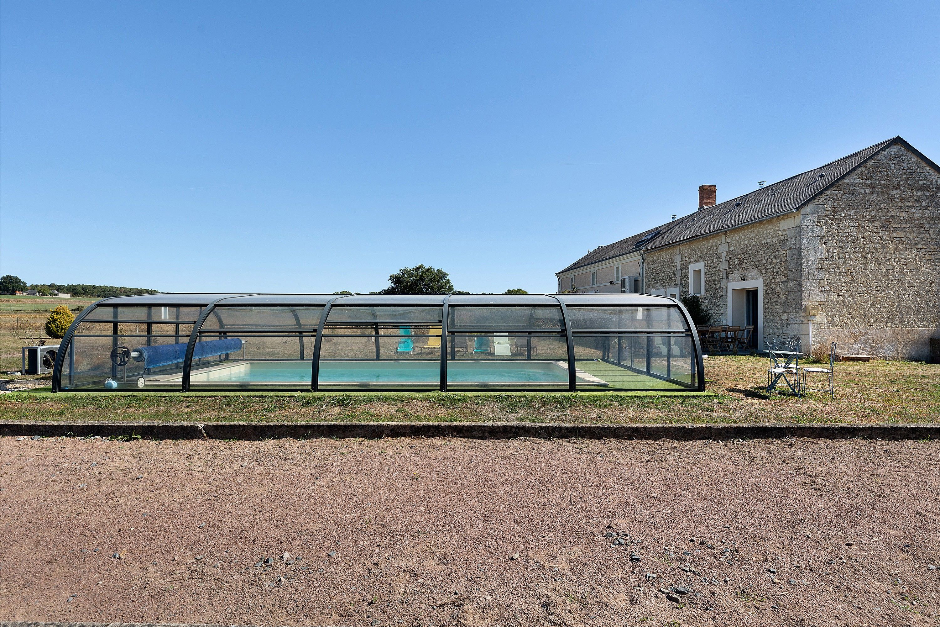 A covered swimming pool with a stone building in the background.