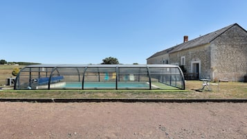 A covered swimming pool with a stone building in the background.