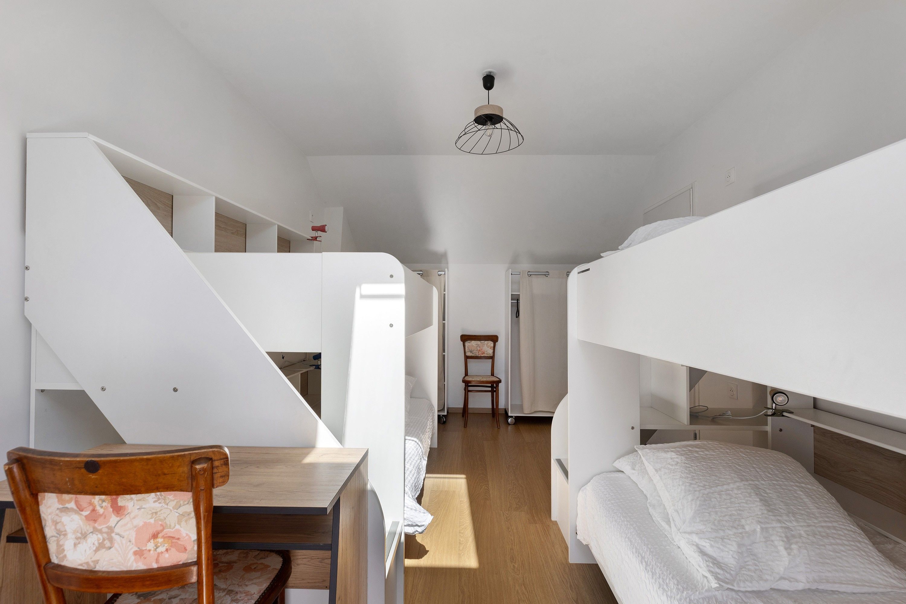 A compact room with bunk beds, a desk, and a chair.