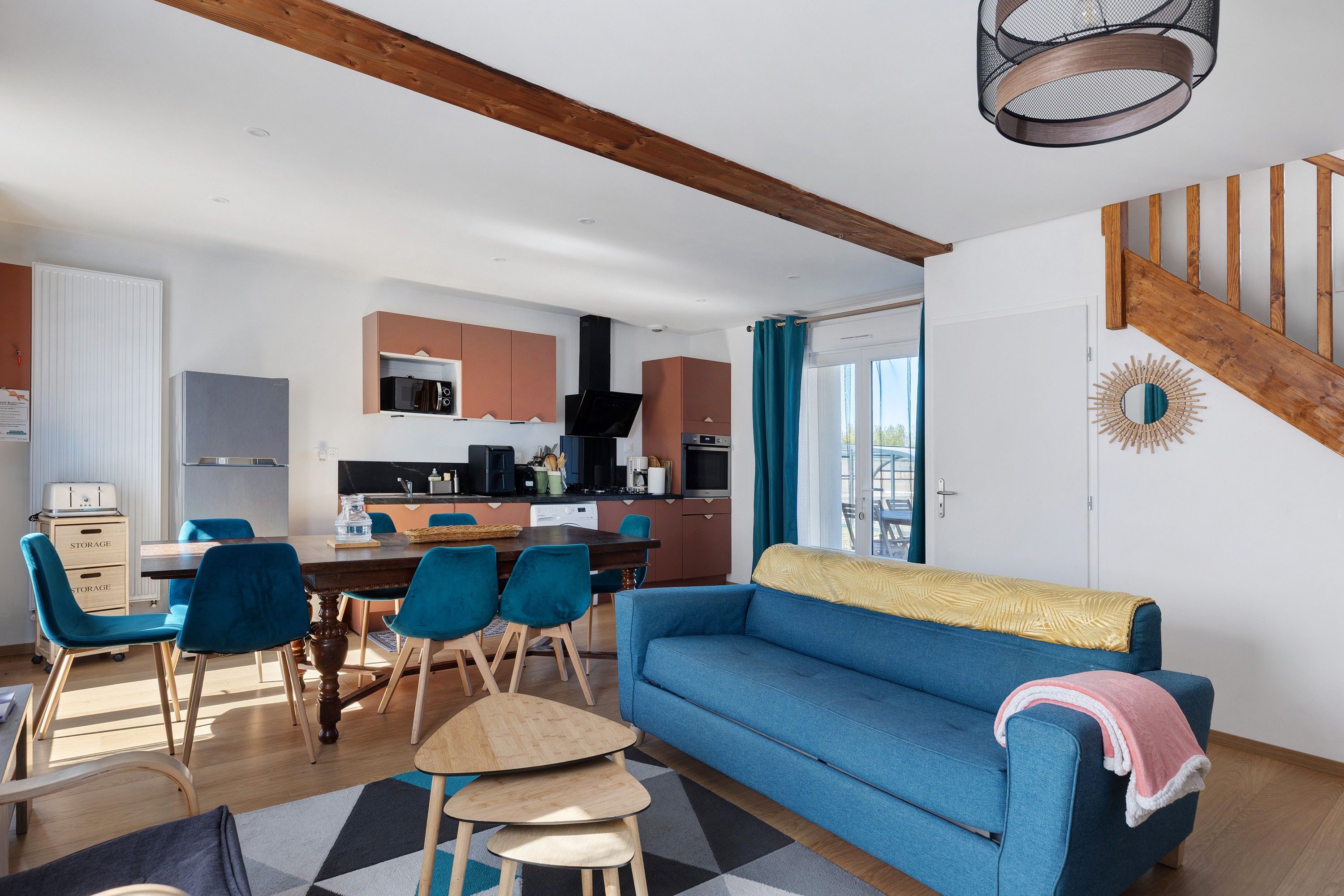 Un espacio moderno tipo sala de estar con comedor, cocina y un sofá azul.