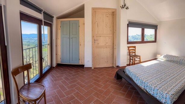 A bedroom with a bed, a chair, a window, and a door. - Tenuta San Lorenzo - Relax Among Vineyards and Olive Groves (Monte san savino)