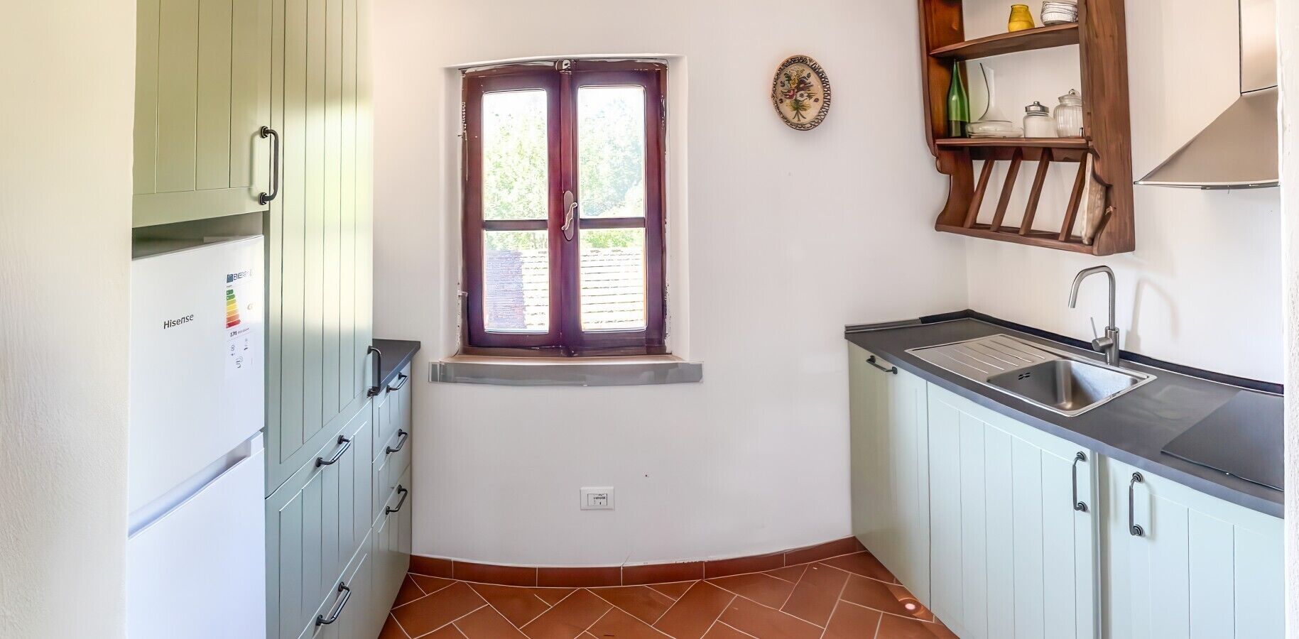 Una cucina compatta con finestra, lavello e mobiletto a incasso.