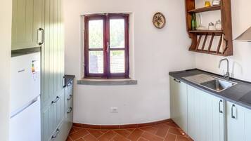 Una cucina compatta con finestra, lavello e mobiletto a incasso.