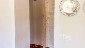 A hallway with a brick archway, a wooden door, and two wall-mounted decorative plates. - Tenuta San Lorenzo - Relax Among Vineyards and Olive Groves (Monte san savino)