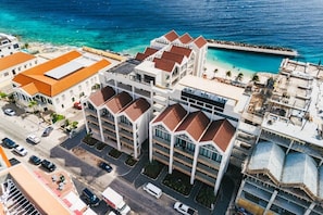 Ein mehrstöckiges Hotel mit Innenhof, neben einem Strand und einem Schwimmbad.