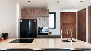 Uma cozinha moderna com geladeira preta, forno embutido, pia e bancada de mármore.