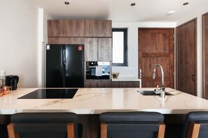 Eine moderne Küche mit einem schwarzen Kühlschrank, einem Einbauofen, einer Spüle und einer Marmorarbeitsplatte.