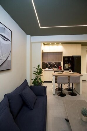 Un salon moderne avec un canapé foncé et un coin repas comprenant deux chaises.