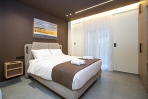 A modern hotel room with a large bed, a bedside table, and a wardrobe. - Luxury apartments near athens city center (Athina)