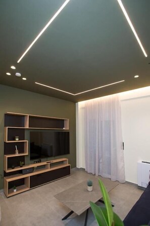 A modern living room with a flat-screen TV, built-in shelving, and a minimalist design. - Luxury apartments near athens city center (Athina)