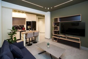 A modern living room with a sofa, a coffee table, and a TV mounted on the wall. - Luxury apartments near athens city center (Athina)