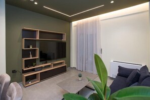 A modern living room with a flat-screen TV, built-in shelves, a coffee table, and a sofa. - Luxury apartments near athens city center (Athina)
