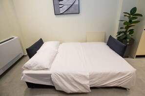 Un lit bien fait, avec des draps blancs, un seul oreiller et une tête de lit.