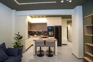 Une cuisine moderne avec un dosseret en marbre, un îlot central doté de tabourets et un réfrigérateur encastré.