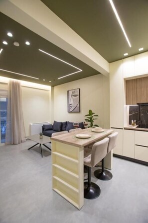 A modern kitchen with a dining area, a sofa, and a window. - Luxury apartments near athens city center (Athina)