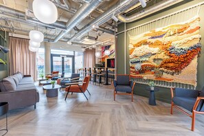 Ein modernes Interieur mit Sitzgelegenheiten, einer großen Wandteppich und freiliegenden Lüftungsrohren.