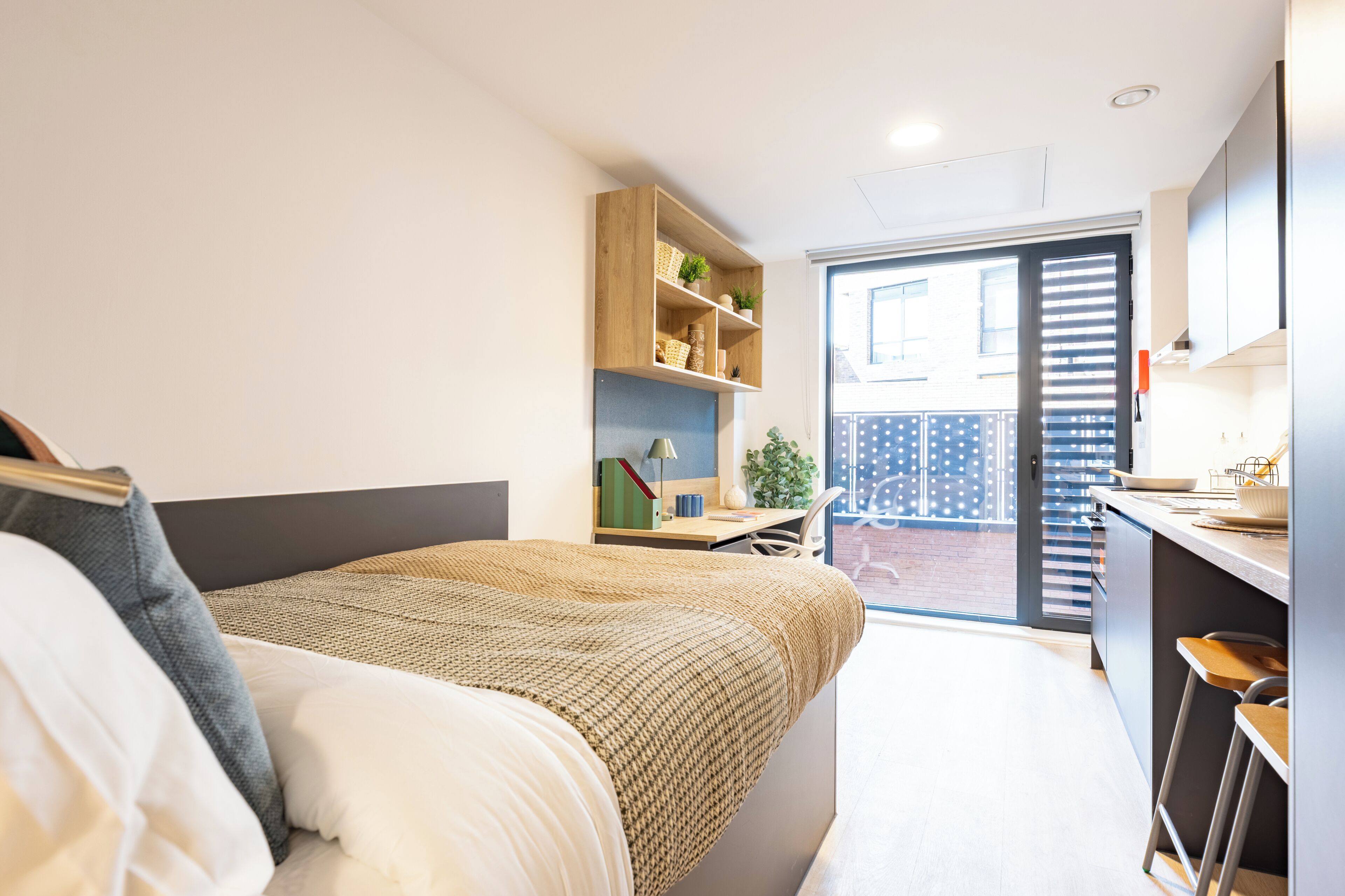 A modern bedroom with a bed, a desk, and a shelving unit.