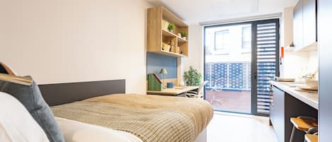 A modern bedroom with a bed, a desk, and a shelving unit.
