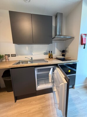 A modern kitchen with a built-in dishwasher, a stainless steel sink, and a range hood. - Student Only Fabric (Nottingham)