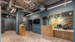 Een modern ontworpen receptiezone, met een houten receptiebalie, een groot wanddisplay en een vloer met een patroon.