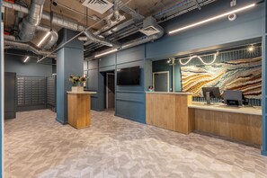 Ein Empfangsbereich mit modernem Design, der ein Holzbüro, einen großen Wandbildschirm und einen gemusterten Boden zeigt.