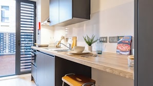 Een moderne keuken met een ingebouwde oven, een spoelbak en een eetgedeelte met krukjes.