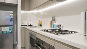 Et moderne køkken med et rustfrit stål køleskab, en indbygget opvaskemaskine, en gas komfur og en vask.