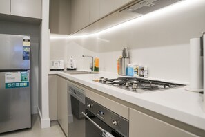 Eine moderne Küche mit einem Edelstahl-Kühlschrank, einem eingebauten Geschirrspüler, einem Gasherd und einer Spüle.