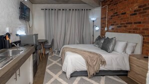 A compact hotel room with a bed, bedside table, and a small kitchenette. - The 260 Collection Luxury City Apartment (Johannesburg)