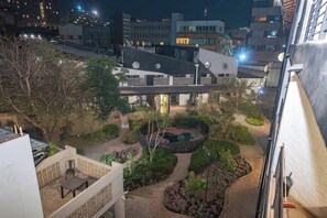 Ein Dachgarten mit Whirlpool, umgeben von Grünpflanzen und einem gepflasterten Weg.