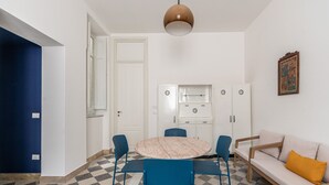 En kompakt opholdsstue med et rundt bord, blå stole, en sofa og et tekøkken.