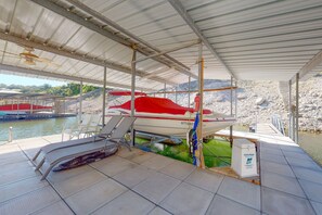 A boat docked under a covered area with a water body in the background. - Lake Travis Waterfront Home with Dock Access | 4BR (Lakeway)