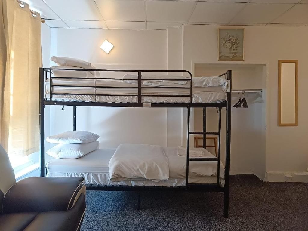 A bunk bed room with a desk and chair, a small closet, and a painting on the wall.