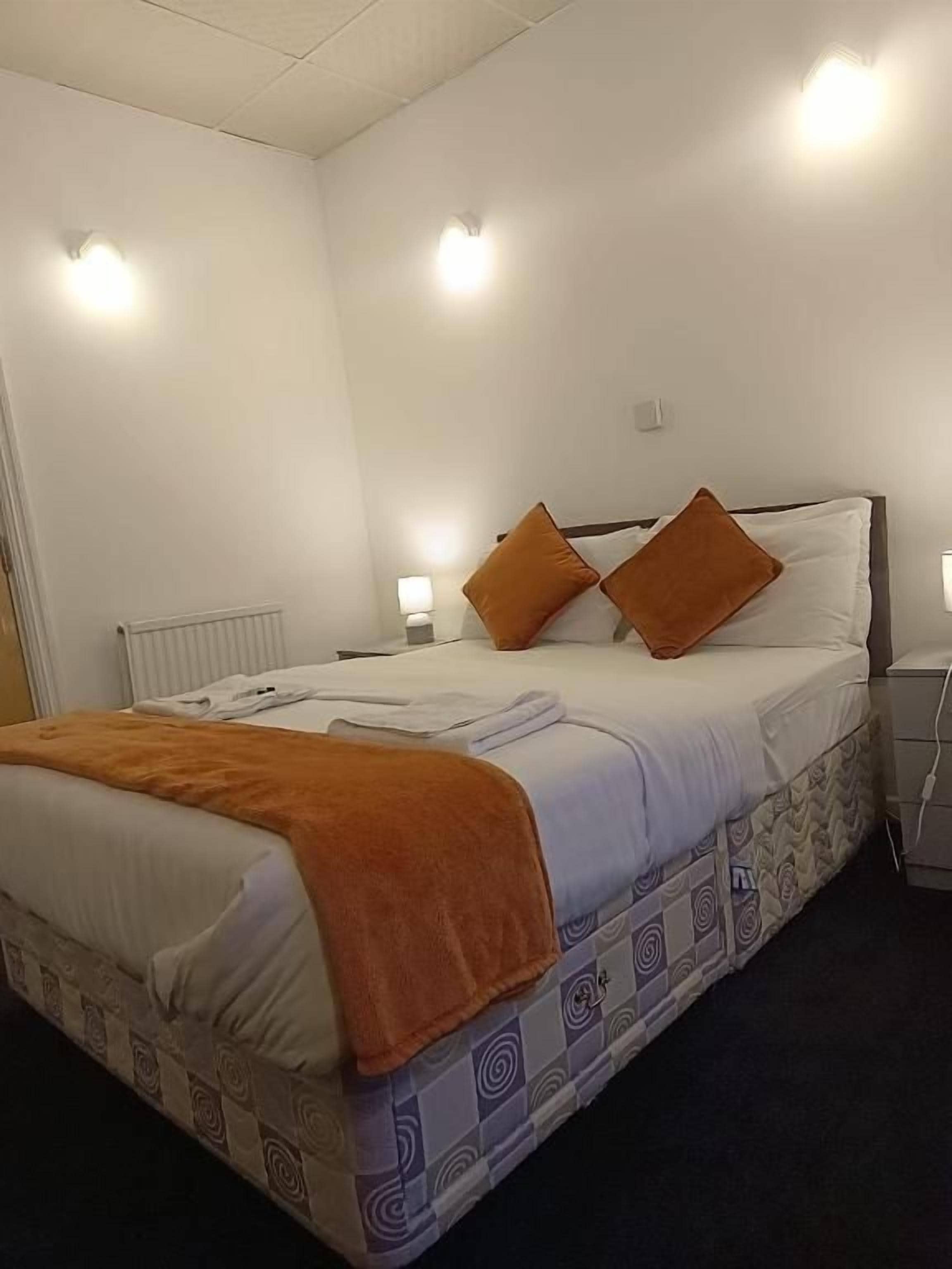 A neatly made bed with a patterned bedspread, two pillows, and a blanket.