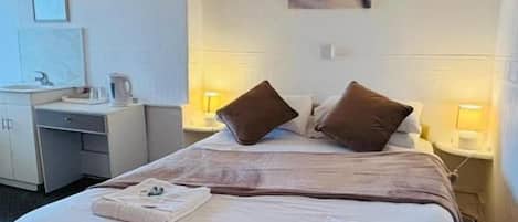 Une chambre d’hôtel avec un lit, des lampes de chevet, un bureau et un miroir.
