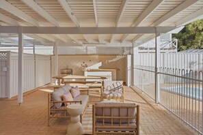 An outdoor patio area with a pool, covered seating, and a decorative fence. - Mediterranean Beachside retreat with a pool (Broadwater)
