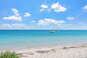 A beach with clear turquoise water, a sandy shore, and two sailboats anchored in the distance. - Mediterranean Beachside retreat with a pool (Broadwater)