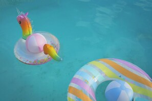 Ein Pool mit aufblasbaren Spielzeugen, darunter ein Einhorn und ein gestreifter Ring.