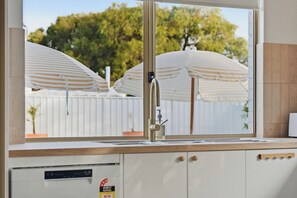 A kitchen with a window, a faucet, and a dishwashing machine. - Mediterranean Beachside retreat with a pool (Broadwater)