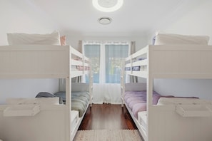 Ein Schlafzimmer mit Etagenbetten, einem Fenster, einem Deckenventilator und einem Teppichboden.