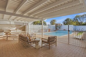 An outdoor patio area with a pool, covered seating, and a fenced swimming area. - Mediterranean Beachside retreat with a pool (Broadwater)