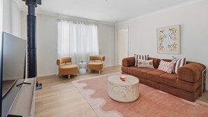 Una sala de estar con sofá, dos sillones, una mesa de centro, televisor y chimenea.