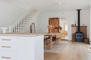 Eine Küche mit einem Holzespeisetisch, weißen Schränken und einer Treppe.