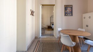 Ein Flur, der in ein Schlafzimmer mit einem Bett, einem Sessel und einem Tisch mit Stühlen führt.