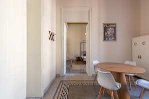 A hallway leading to a bedroom with a bed, a chair, and a table with chairs. - Roma 1923 - Casa Rossa by Wonderful Italy (Palermo)