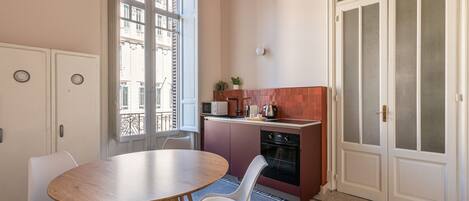 Une cuisine compacte avec un coin repas, un four encastré et une vue par la fenêtre.