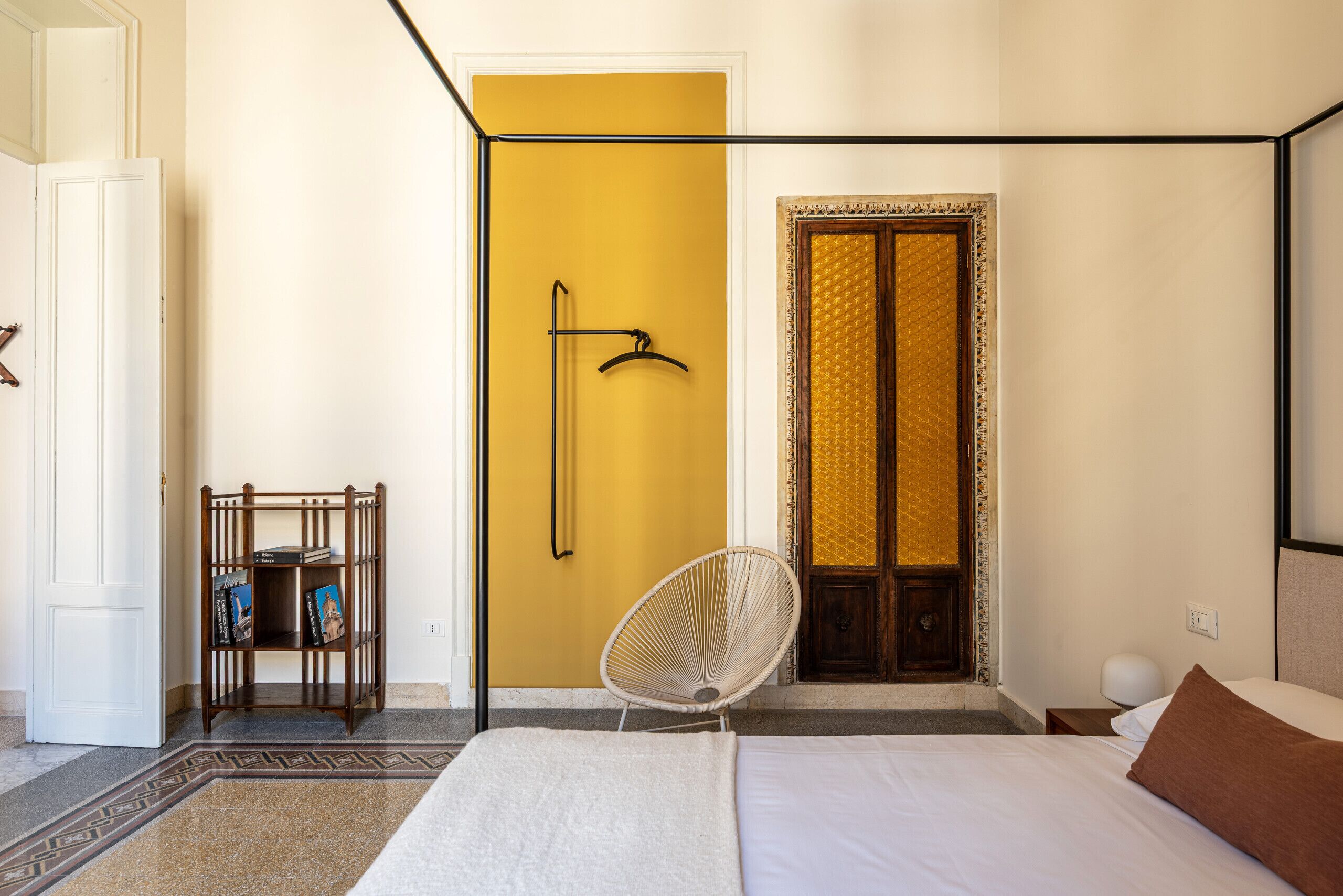 Une chambre à coucher comprenant un lit, une chaise, une bibliothèque et une porte au design original.